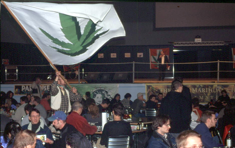 In der menschengefüllten Halle schwingt ein Mann eine grosse Cannabisflagge.