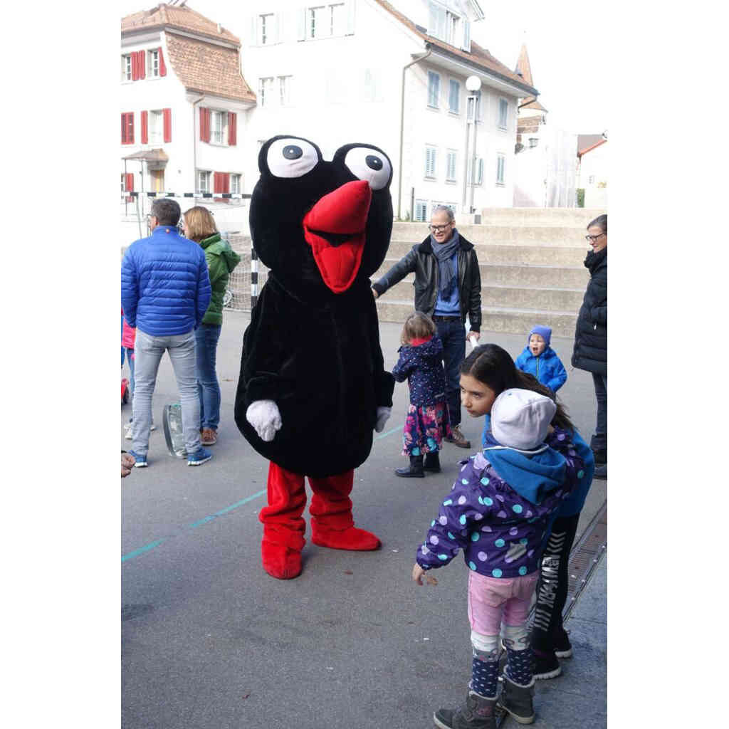 Das Maskottchen des Abraxas Raben begrusst Kinder auf dem Pausenplatz.