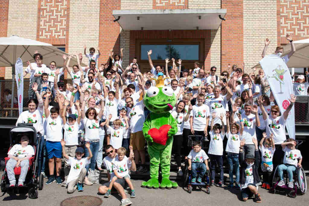 Gruppenfoto mit Kindern und Maskottchen vor Gebäude