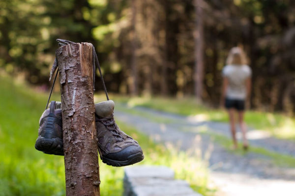 Wanderschuhe hängen an Pfahl im Wald