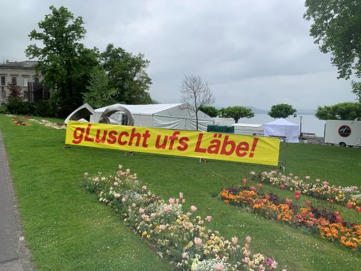 Plakat für Gluscht.World an der Seepromenade Zug