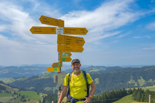 Corrado Filipponi steht vor einem Wegweiser, hinter ihm eine sonnige Landschaft.