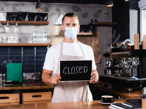 Mann mit Maske hinter Tresen im Kaffee