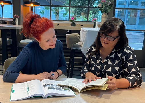 Den beiden Co-Leiterinnen des LABfor Kids Barbara Windholz und Claudia Castro sitzen am Tisch und schauen in ein Buch