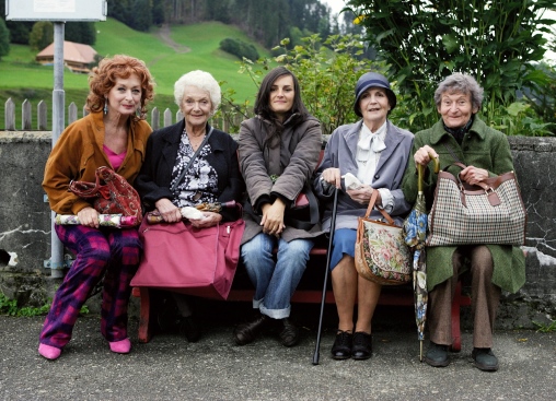 Gruppenfoto von Die Herbstzeitlosen mit Regisseurin Bettina Oberli. Sie sitzen auf einer Bank