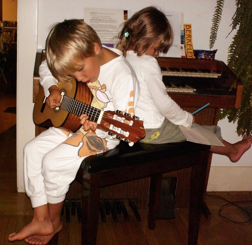 Die junge Joya Marleen und ihr Bruder Maurus sitzen auf einem Stuhl und musizieren