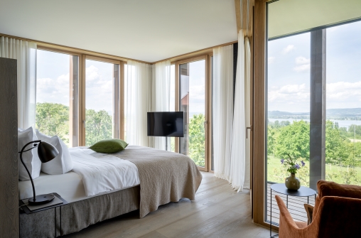 Blick in ein Hotelzimmer mit Bett und grosser Fensterfront